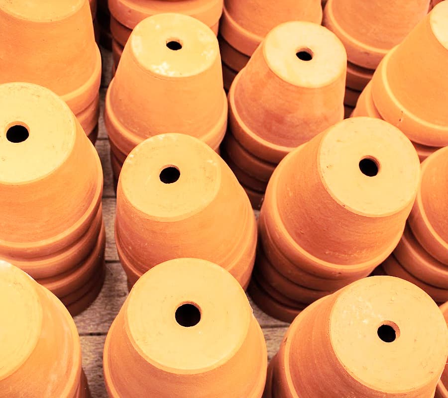 stacks of orange terracotta pots with drainage holes